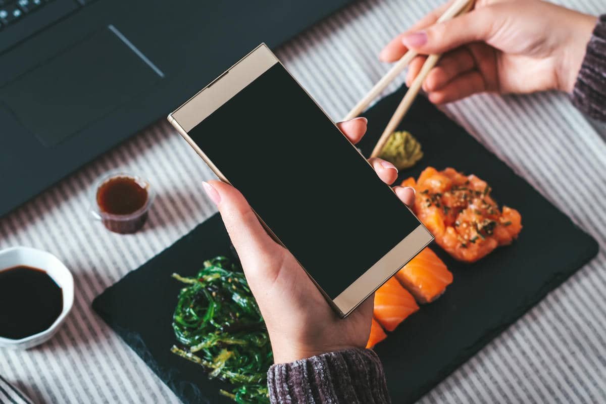 Persona con el móvil buscando un plato de sushi, afectada por una carta pdf restaurante no indexable