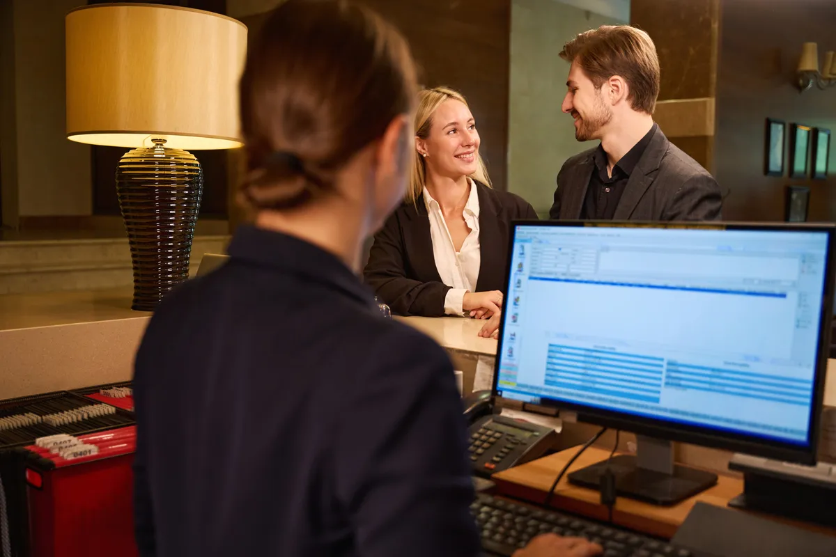Recepción de hotel gestionando el check-in para fomentar reservas directas sin Booking