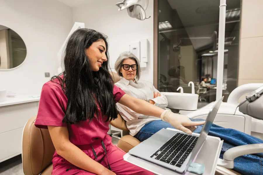Dentista mostrando resultados en portátil, ejemplo de página web clínica dental